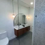 bathroom remodel with large mirrors and floating cabinet
